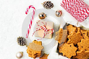 Stack of Christmas shortbread cookies with hazelnuts in star shape golden balls pine cones candy cane gift box on snowy background