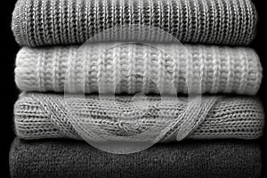 Stack of chunky knitted sweaters folded neatly, featuring various rib and cable knit textures