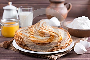 Stack of classic Russian thin pancakes bliny or crepes with honey on a plate. Traditional for the Russian pancake week Maslenit photo