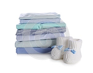 Stack of clean baby`s clothes and small booties on white background