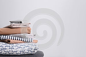Stack of clean bed linen and pillow on light grey background. Space for text