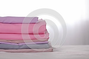 Stack of clean color folded linens on bed. Space for text