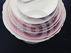 Stack of clean empty plates on black background, dishware and table decor