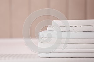 Stack of clean folded linens on bed indoors. Space for text