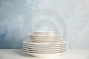 Stack of clean plates on table against blue background. Space for text