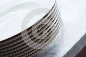 Stack of clean plates on the table. Clean prepared dishes on a white table in the kitchen.