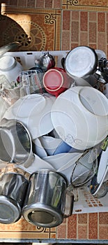Stack of Clean Tableware on Drying Rack: Spoons, Glasses, Plates, and Bowls.