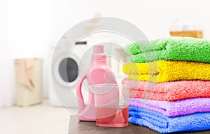 Stack of clean towels and softener on table in laundry room