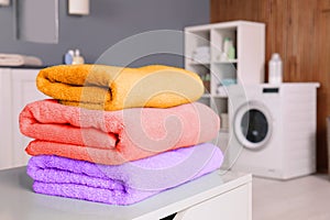 Stack of clean towels on table in laundry room.