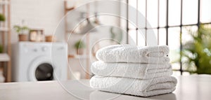 The stack of clean white towels in a bright modern laundry room. AI generated image