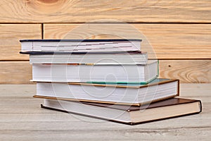 Stack of closed books on wooden background.