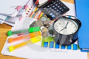 The stack of coins with business paper graphs and pencil with charts report, calculator concept of calculating expenses, incomes