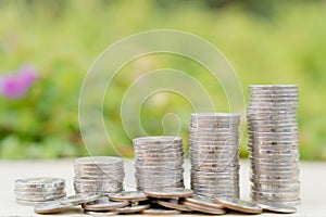 Stack coins on blurred green natural background. Property investment and house mortgage financial concept