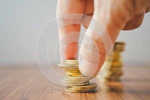 Stack of coins in blurred senior human hand on wood , business and finance background