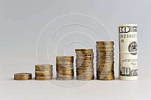 A stack of coins and bundle of dollars