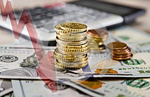 Stack of coins with a calculator and dollars on the background of a business graph. The concept of financial growth or decline.