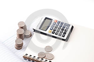 Stack of coins, calculator, notebook on white background