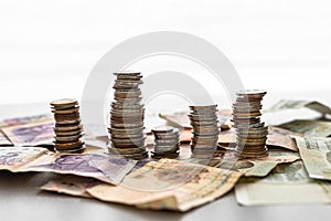 Stack of coins dollar euro ruble yuan franc yen pound zloty rupee crowns on a background of banknotes