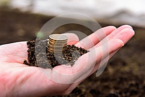 Stack of coins on hand with ground.