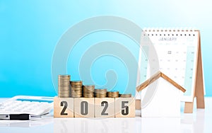 A stack of coins, a house model, and 2025 calendar placed together on a table. Represents the concept of mortgage planning,