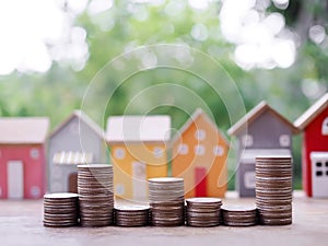 Stack of coins with miniature house background. The concept of saving money for house, Property investment, House mortgage, Real