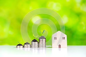 Stack of coins with plant growing and house with green nature background, Saving money for property investment concept