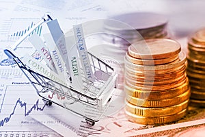 Stack of coins and a trolley with various types of financial investment products. photo