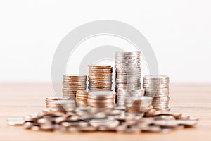 Stack of coins on wooden desk for saving money