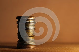 A stack of coins on a wooden shelf.