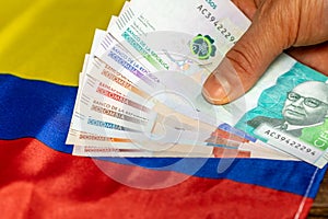 A stack of Colombian pesos held in hand against the background of the flag of Colombia, Business concept, economic analysis,