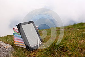 Stack of colorful books and electronic book reader