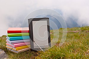 Stack of colorful books and electronic book reader