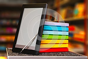 Stack of colorful books with electronic book reader