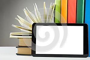 Stack of colorful books and electronic book reader. Electronic library concept. Back to school. Copy space