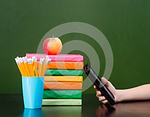 Stack of colorful books with electronic book reader near empty green chalkboard. Sample for text