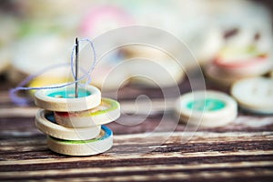 Stack of colorful buttons with sewing needle