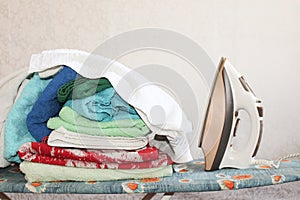Stack of colorful clean towels  on grey background. Ironing clothes on ironing board. Stack of clean towels on table.