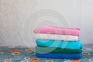 Stack of colorful clean towels  on grey background. Ironing clothes on ironing board. Stack of clean towels on table. Colored towe