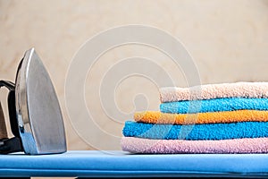 Stack of colorful clean towels on white background. Ironing clothes on ironing board. Stack of clean towels on table. Colored