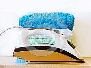 Stack of colorful clean towels  on white background. Ironing clothes on ironing board. Stack of clean towels on table. Colored tow