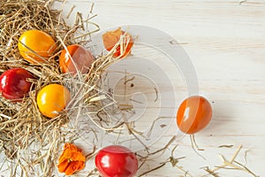 Stack of colorful easter eggs on straw with wooden table background