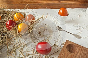 Stack of colorful easter eggs on straw with wooden table background