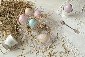 Stack of colorful easter eggs on straw with wooden table background