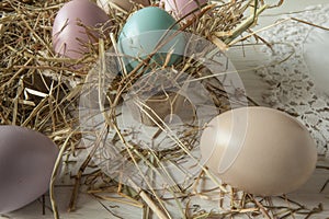 Stack of colorful easter eggs on straw with wooden table background