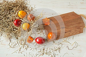 Stack of colorful easter eggs on straw with wooden table background