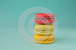 Stack of colorful macaroons stacked up like a tower in turquose pastel background.