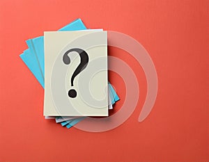 Paper notes with question marks on Coral background, flat lay. Space for text