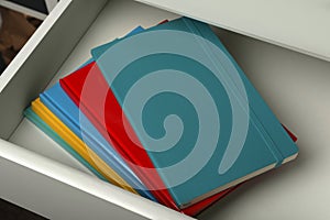 Stack of colorful planners in open drawer, closeup