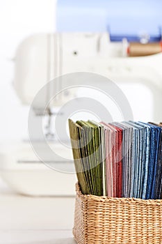 Stack of colorful quilting fabrics in basket on the background of sewing machine