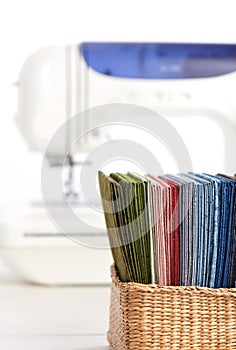 Stack of colorful quilting fabrics in basket on the background of sewing machine